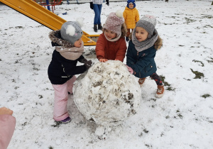 Marysia, Laura i Laura toczą śniegową kulę.