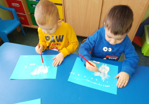 Piotruś i Hubert malują krajobraz zimowy białą farbą.