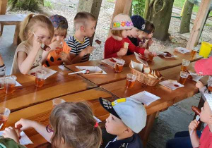 Dzieci jedzą kiełbaski.
