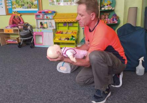 Pan Leszek, ratownik medyczny demonstruje jak postępować z dzieckiem na małym fantomie.