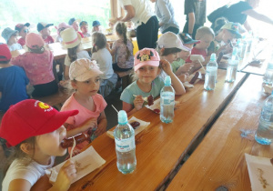 Dzieci jedzą kiełbaski z grilla.