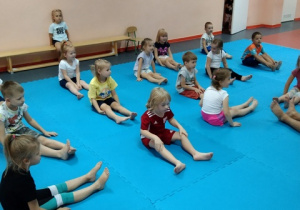Dzieci wykonują ćwiczenia w pozycji siedzacej.