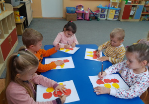 Dzieci malują kredkami koszyczki z owocami.
