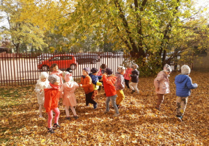 Dzieci skaczą po liściach.