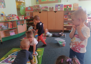 Dzieci wspólnie bawią się na dywanie.