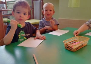 Mateusz i Nikodem z zadowoleniem rysują swoje pierwsze rysunki przy stoliku.