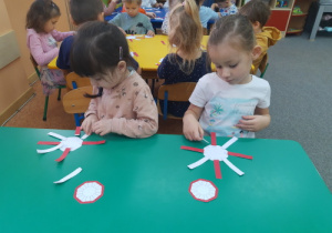 Dziewczynki układają biało-czerwone wstążki.