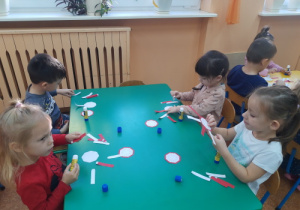 Dzieci przyklejają biało-czerwone wstążki.