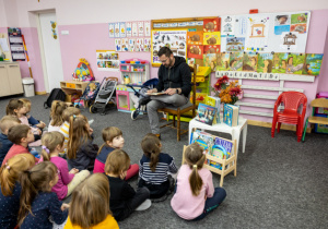 Dzieci słuchają książkę z zainteresowaniem.