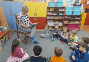 Dzieci słuchają z uwagą czytanej bajki przez babcię Huberta panią Ulę.