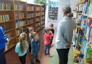 Pani bibliotekarka oprowadza dzieci po bibliotece.