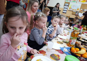 Dzieci jedzą pyszne ciasta przygotowane przez rodziców.