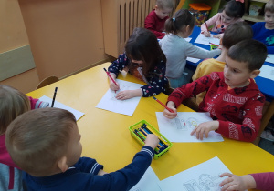 Dzieci kolorują portret "Necia" przy stoliku.