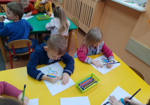Dzieci kolorują portret "Necia" przy stoliku.
