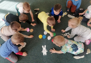Dzieci na dywanie bawią się w zabawę "Jajka do koszyczka".