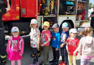 Dzieci czekają na wejście do wozu strażackiego.