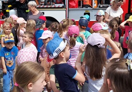 Dzieci słuchają sygnałów dźwiękowych samochodu strażackiego w akcji.