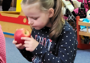 Dziewczynka ogląda jabłko.