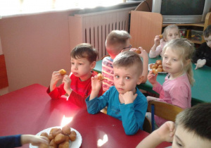 Dzieci jedzą pączki.