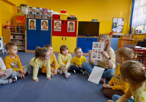 Pani Patrycja pokazuje dzieciom ilustracje przedstawiające różne zachowania.