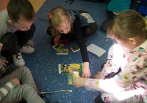 Oskar, Zuzia i Nikola układają bajkowe puzzle.