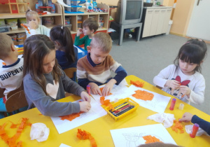 "Biedronki" wyklejają dynię pomarańczową bibułą.