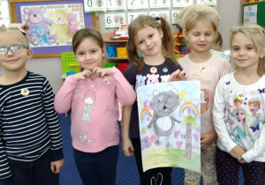 Dziewczynki prezentują wspólnie narysowanego misia.